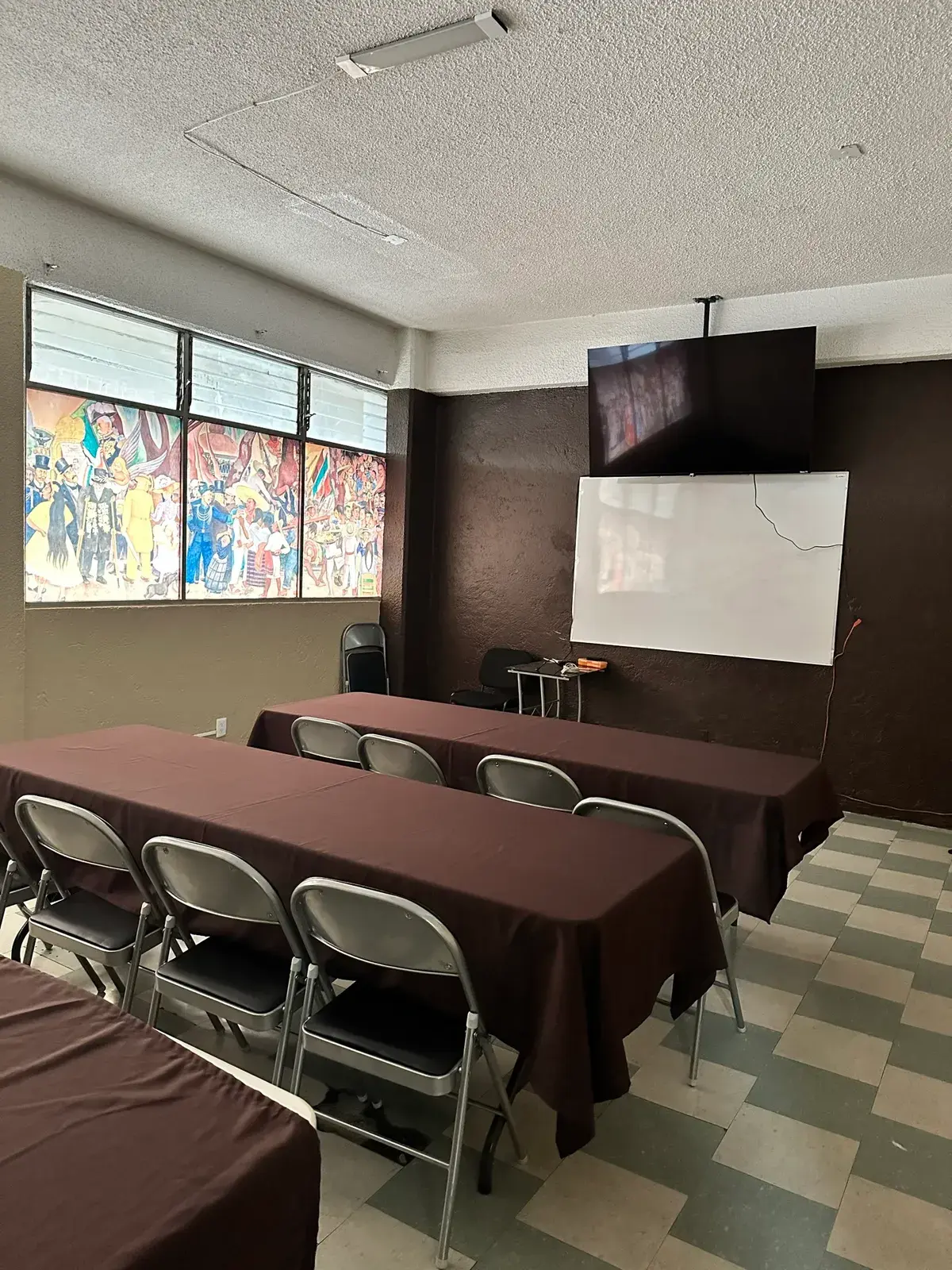 Sala de usos múltiples de CADE con pantalla y mural